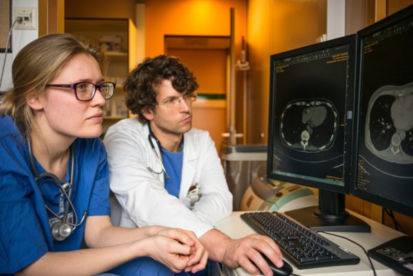 Two doctors look at scans on a screen